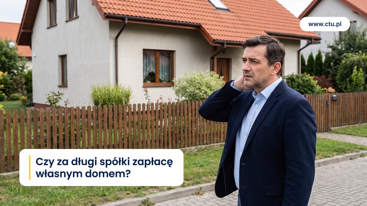 Mężczyzna w marynarce stoi z ręką na karku przed domem jednorodzinnym i patrzy na niego z troską