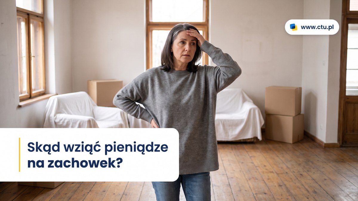 Kobieta stoi w prawie pustym salonie starego domu wśród zasłoniętych mebli i kartonów.